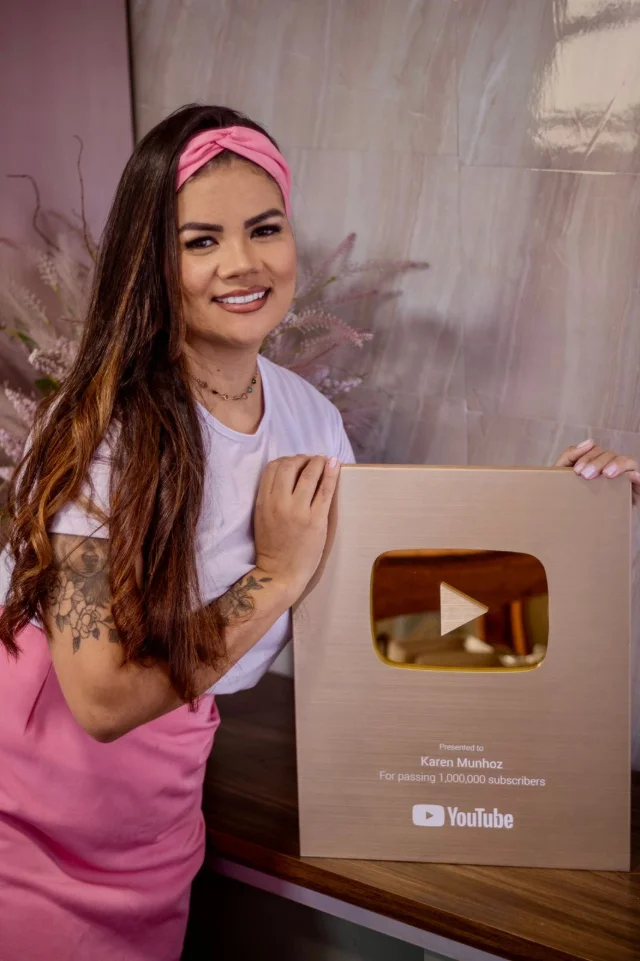 Karen Munhoz segurando a placa de 1 milhão de inscritos do YouTube